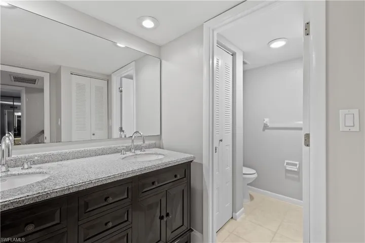 Full bathroom featuring a closet, double vanity, and light tile patterned floors