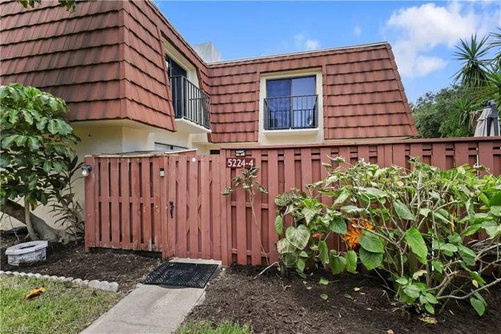 View of side of home featuring mansard roof and a tiled roof