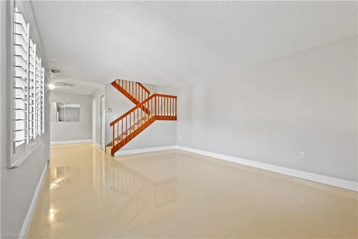 Spare room featuring light tile patterned floors, a textured ceiling, and stairway