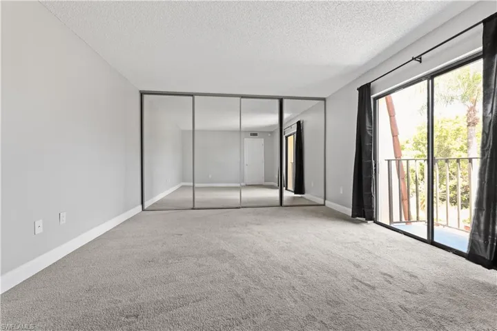 Unfurnished bedroom featuring carpet flooring, access to exterior, a textured ceiling, and a closet