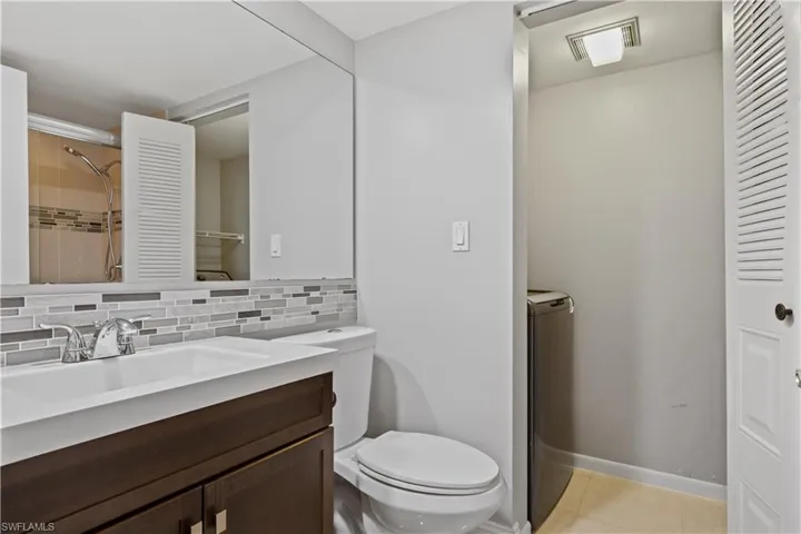 Full bath with tasteful backsplash, vanity, light tile patterned flooring, and washer / dryer