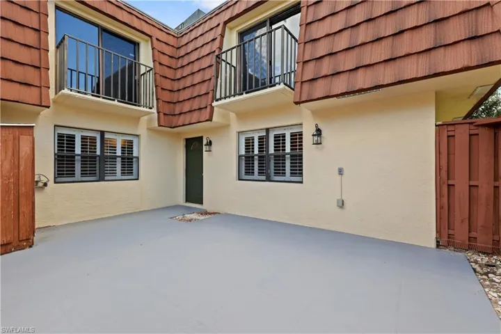 Entrance to property featuring mansard roof, stucco siding, and a patio