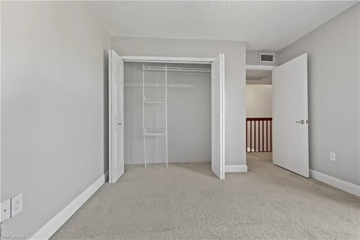 Unfurnished bedroom featuring light carpet, a textured ceiling, and a closet