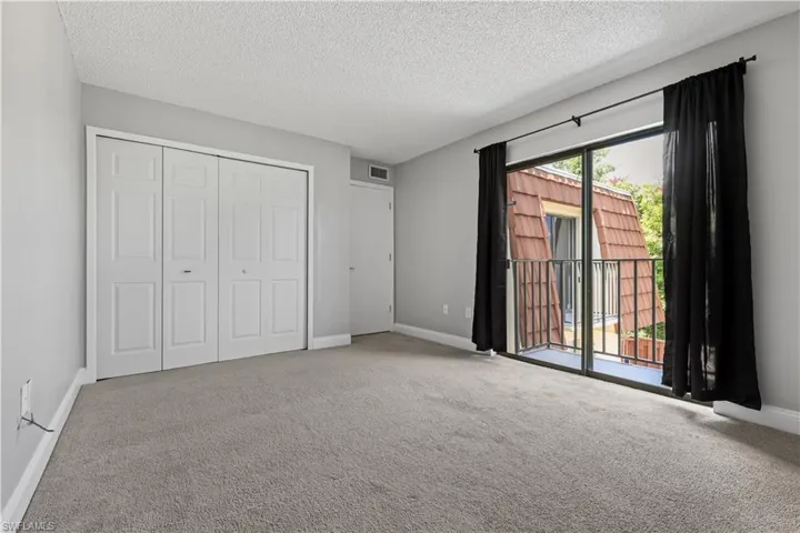 Unfurnished bedroom featuring carpet, a textured ceiling, a closet, and access to outside