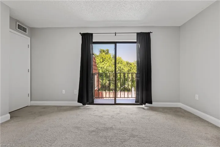 Empty room featuring light colored carpet and a textured ceiling