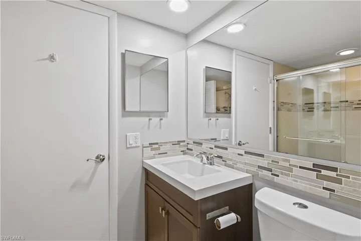 Bathroom featuring tasteful backsplash, vanity, a shower stall, and recessed lighting