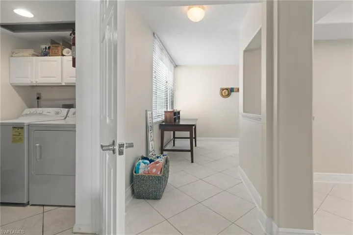 Washroom featuring separate washer and dryer, light tile patterned flooring, cabinets, and a textured ceiling