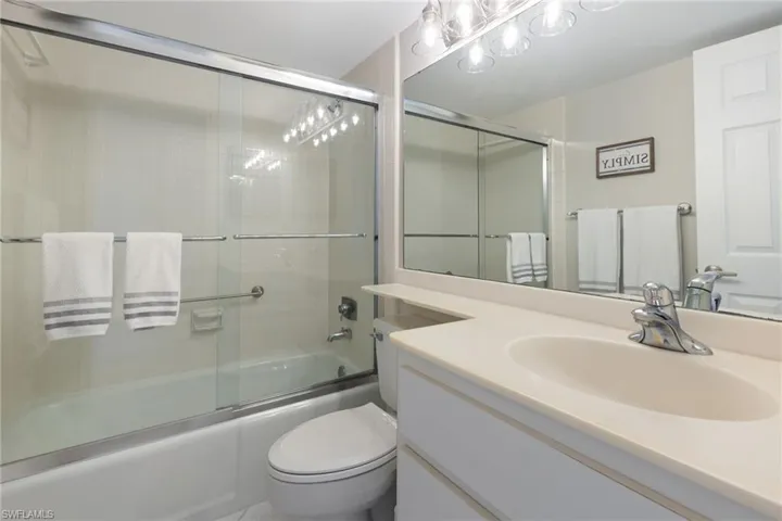 Full bathroom featuring vanity, toilet, and bath / shower combo with glass door
