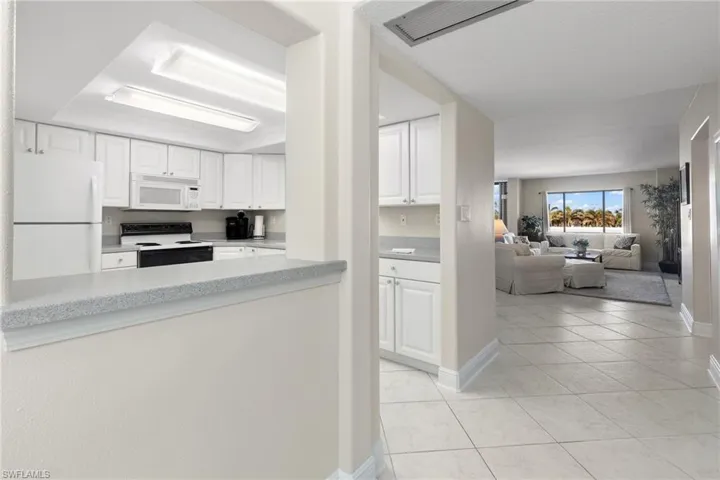 Kitchen with white cabinetry, light tile patterned floors, and white appliances