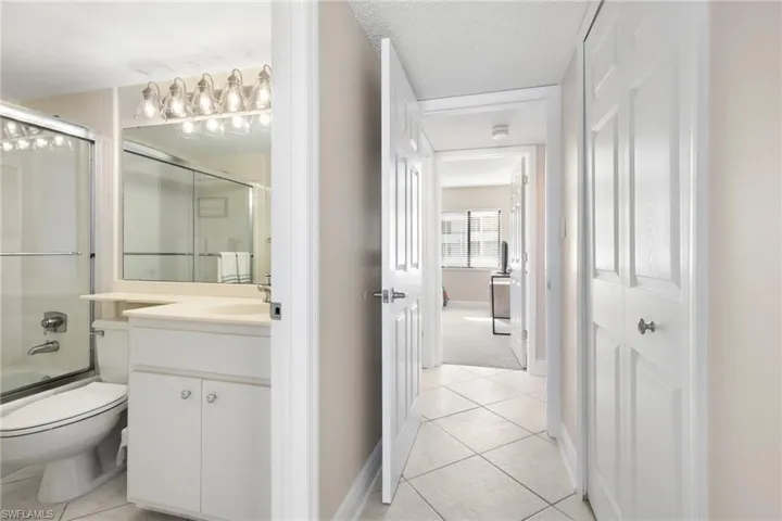 Full bathroom with bath / shower combo with glass door, vanity, a textured ceiling, tile patterned flooring, and toilet