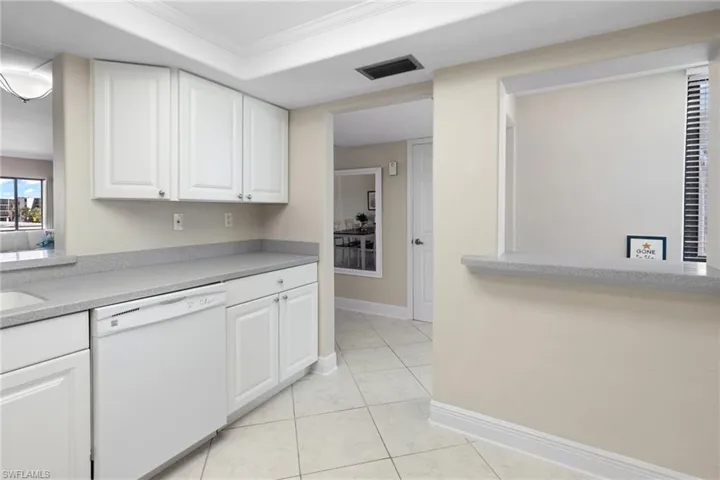 Kitchen featuring dishwasher, light tile patterned floors, white cabinets, and ornamental molding