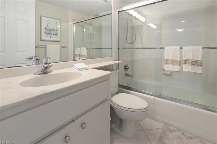 Full bathroom featuring tile patterned floors, combined bath / shower with glass door, toilet, and vanity
