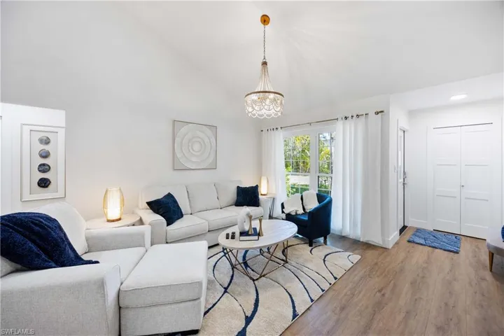 Living room featuring a chandelier, high vaulted ceiling, and light hardwood / wood-style flooring
