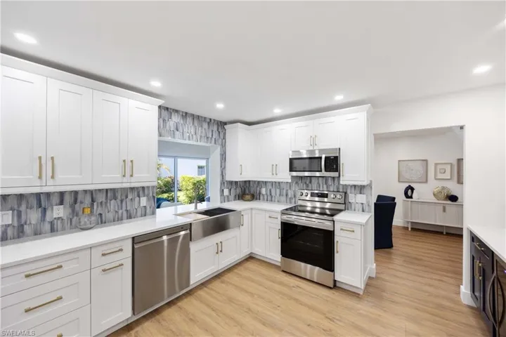 Kitchen featuring stainless steel appliances, white cabinetry, sink, and light hardwood / wood-style floors