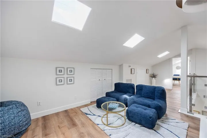 Sitting room featuring vaulted ceiling with skylight and light wood-type flooring