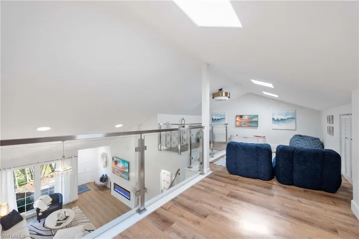 Living room featuring lofted ceiling with skylight and light wood-type flooring