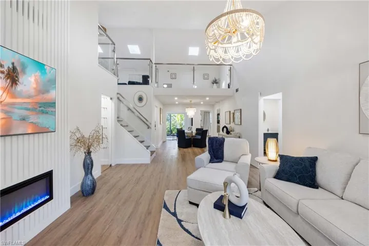 Living room featuring a high ceiling, light hardwood / wood-style flooring, and a notable chandelier