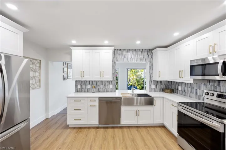 Kitchen with white cabinetry, stainless steel appliances, sink, and light wood-type flooring