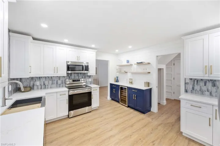 Kitchen featuring sink, stainless steel appliances, wine cooler, white cabinets, and blue cabinets