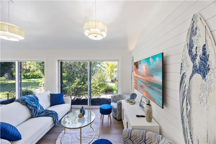 Living room featuring vaulted ceiling, wooden walls, a wealth of natural light, and dark hardwood / wood-style flooring