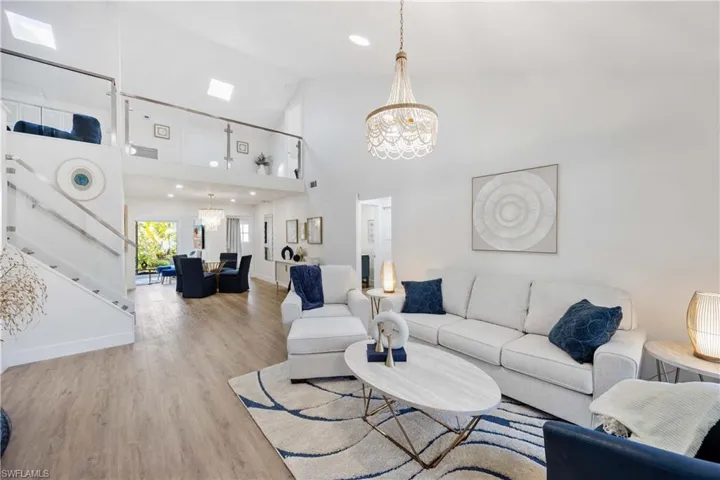 Living room with a notable chandelier, light hardwood / wood-style flooring, and high vaulted ceiling