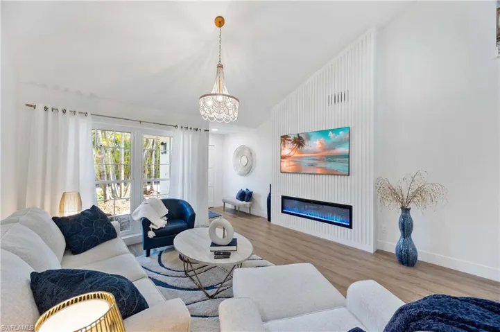 Living room featuring an inviting chandelier, lofted ceiling, and light hardwood / wood-style flooring