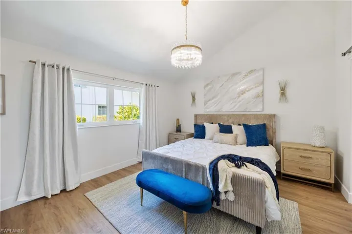 Bedroom with lofted ceiling, a notable chandelier, and light hardwood / wood-style floors