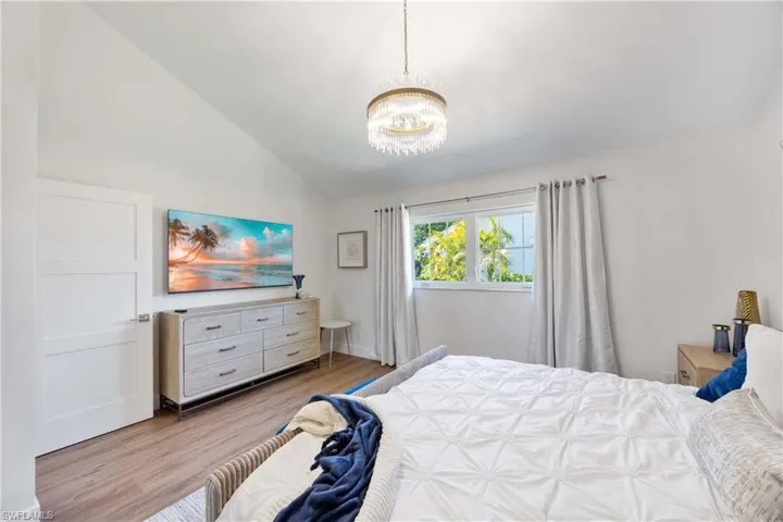 Bedroom with lofted ceiling, a notable chandelier, and light hardwood / wood-style floors
