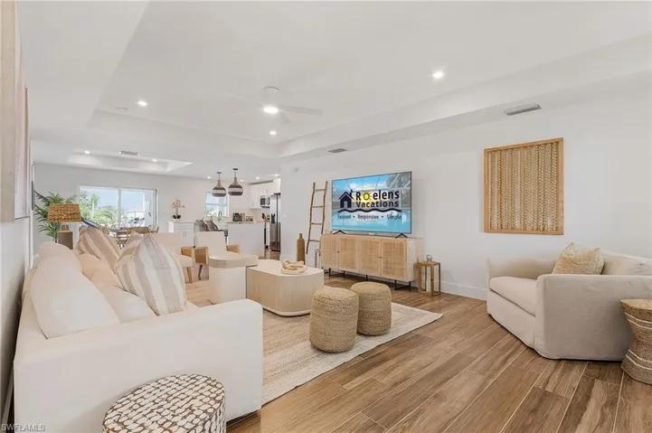 Living room featuring a tray ceiling, ceiling fan, wood finish floors, and recessed lighting