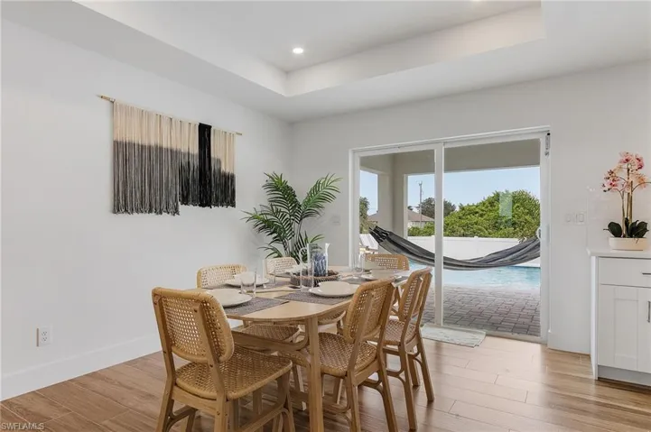 Dining area featuring a raised ceiling, light wood-style floors, and recessed lighting