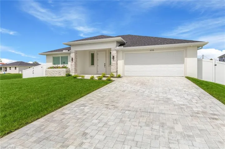 Prairie-style home with a gate, an attached garage, decorative driveway, and stucco siding
