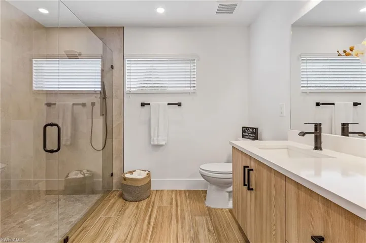 Bathroom with vanity, a stall shower, wood tiled floors, healthy amount of natural light, and recessed lighting