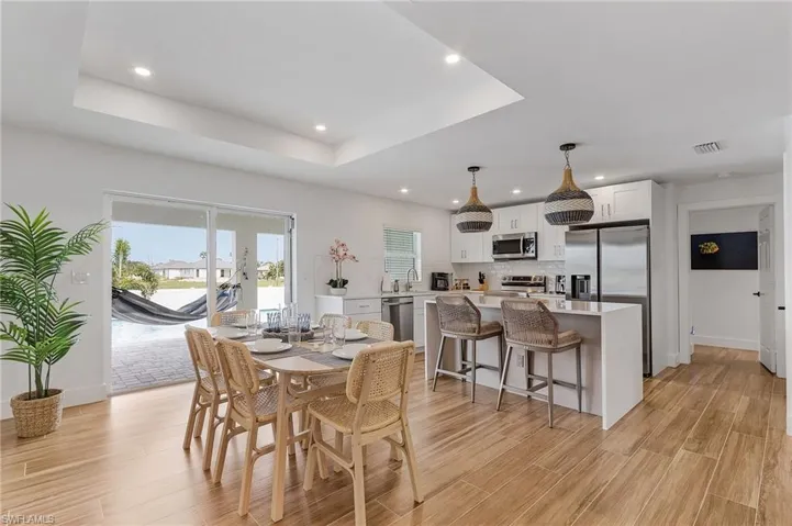 Dining area featuring light wood-style floors, a raised ceiling, and recessed lighting