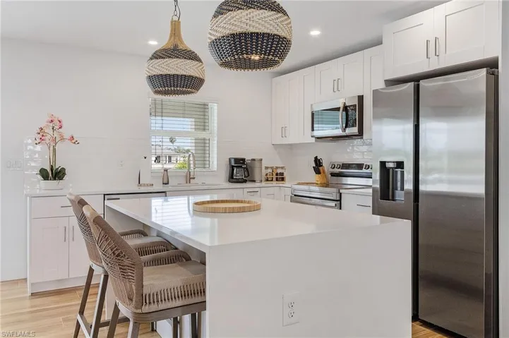 Kitchen featuring stainless steel appliances, a breakfast bar, a center island, and white cabinets