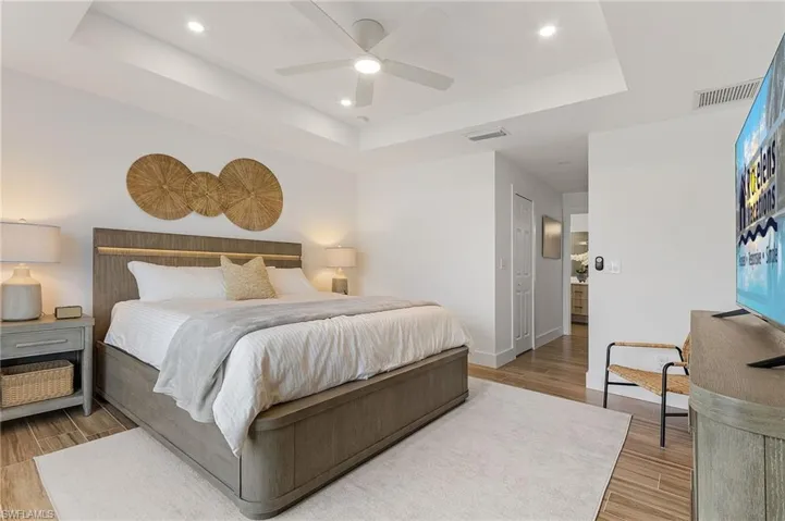 Bedroom with a raised ceiling, light wood-style floors, a ceiling fan, a closet, and recessed lighting
