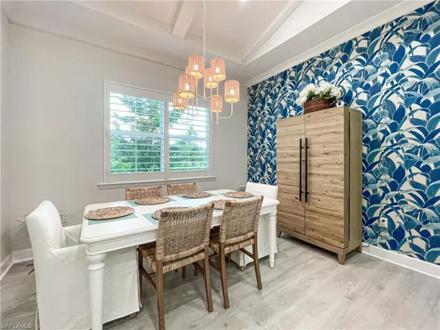 Dining space featuring vaulted ceiling, an inviting chandelier, and hardwood / wood-style flooring
