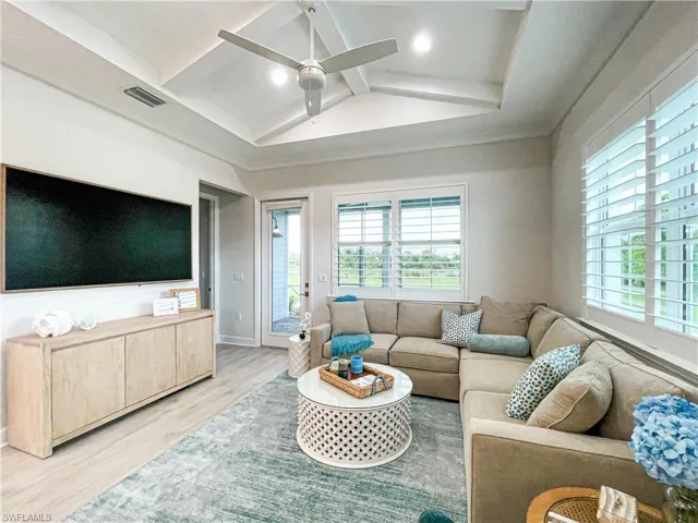 Living room with lofted ceiling with beams, hardwood / wood-style floors, and ceiling fan