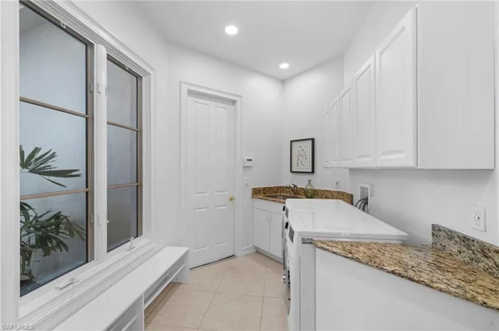 Laundry area featuring hookup for a washing machine, light tile patterned floors, cabinets, and sink