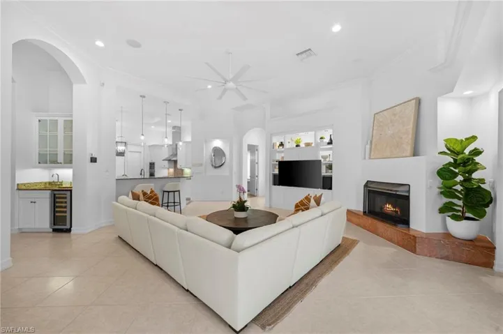 Living room featuring sink, wine cooler, ceiling fan, light tile patterned floors, and ornamental molding