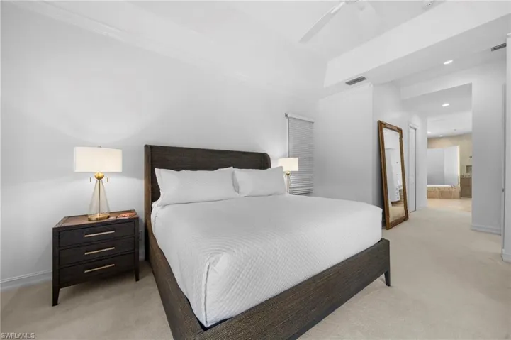 Carpeted bedroom featuring ceiling fan, crown molding, and ensuite bathroom