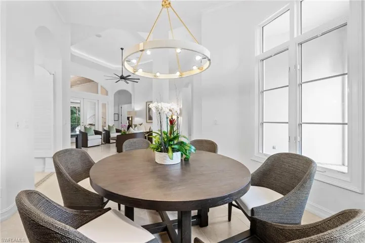 Dining area with ceiling fan with notable chandelier, light tile patterned floors, and ornamental molding