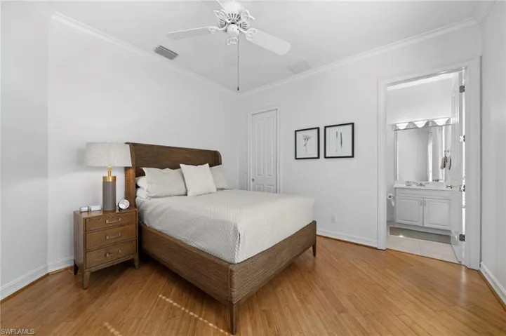 Bedroom featuring ensuite bathroom, ceiling fan, ornamental molding, and light hardwood / wood-style flooring