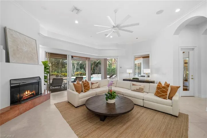 Living room featuring ceiling fan, ornamental molding, and light tile patterned floors