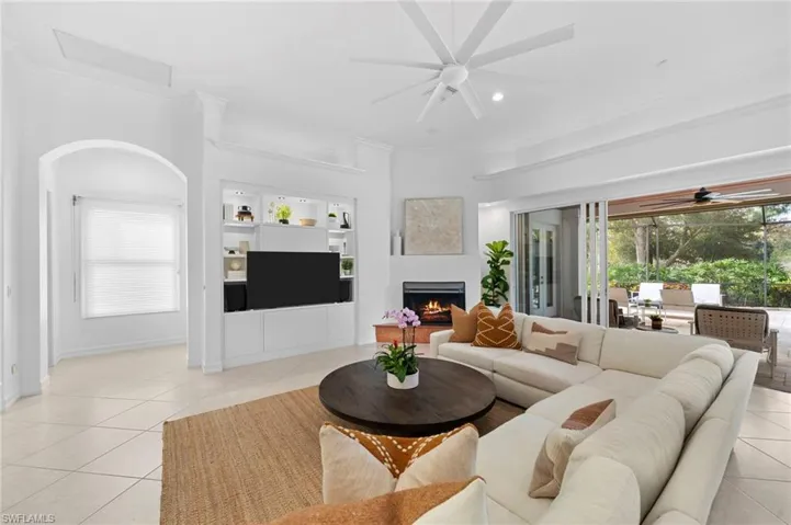 Living room with ceiling fan, light tile patterned floors, and ornamental molding