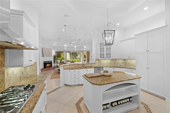 Kitchen featuring a center island, wall chimney range hood, tasteful backsplash, kitchen peninsula, and stainless steel appliances