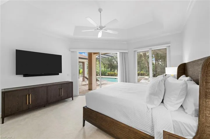 Bedroom featuring a raised ceiling, crown molding, ceiling fan, access to exterior, and light colored carpet