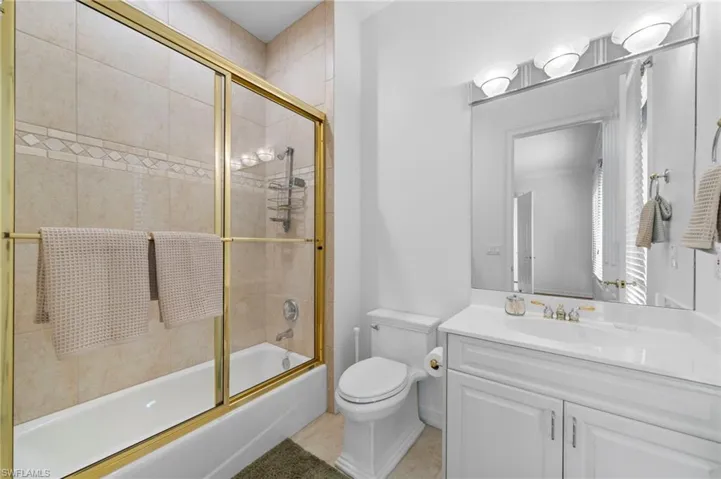 Full bathroom with shower / bath combination with glass door, vanity, and toilet
