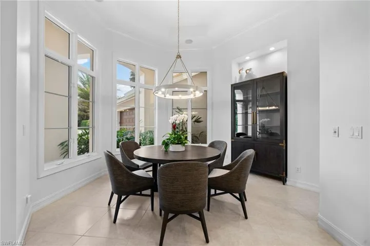 Tiled dining room featuring crown molding and an inviting chandelier