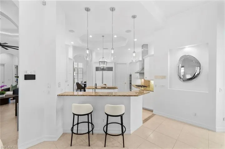 Kitchen featuring light stone countertops, white cabinets, pendant lighting, and ceiling fan