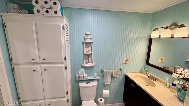 Bathroom with vanity, toilet, and ornamental molding